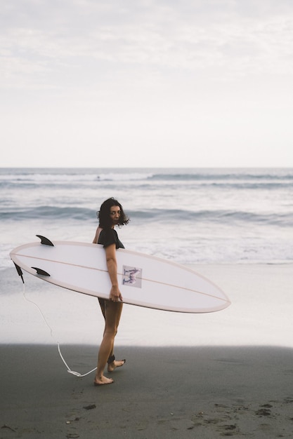 Surfista della donna con la tavola da surf sull'oceano al tramonto