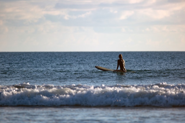 Surfista seduto nell'oceano al tramonto