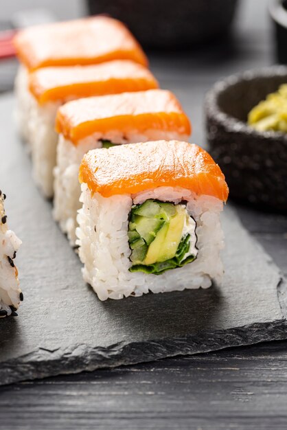 Sushi di maki di color salmone del primo piano sull'ardesia