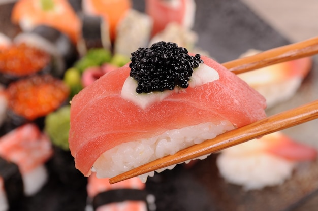 sushi di tonno con caviale tenuto da bacchette