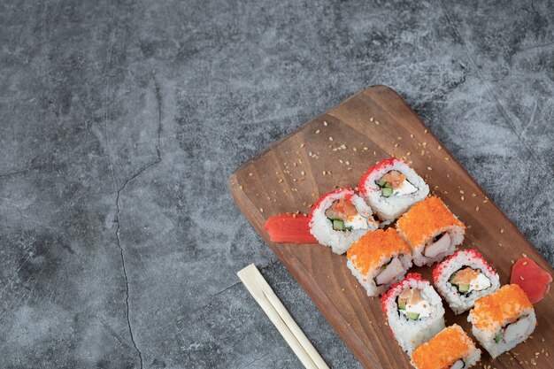 Sushi maki con caviale rosso e crema di formaggio su una tavola di legno.