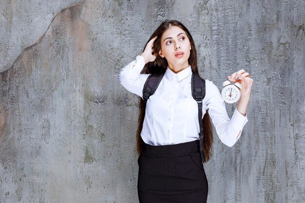 Sveglia della holding della studentessa dai capelli lunghi. Foto di alta qualità