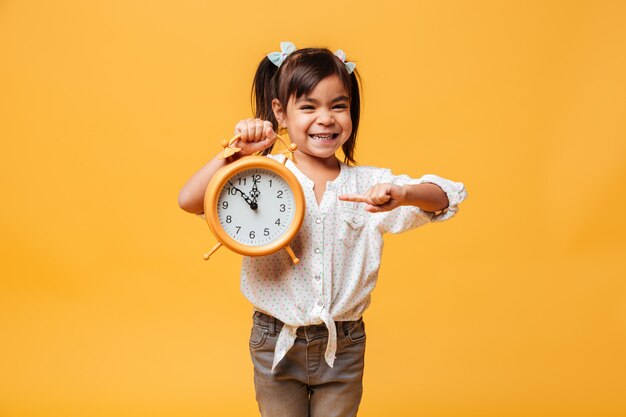 Sveglia sorridente dell'orologio della tenuta del bambino della bambina.