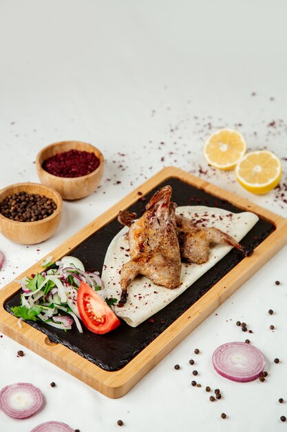 Tabacco di pollo con cipolle su una tavola di legno