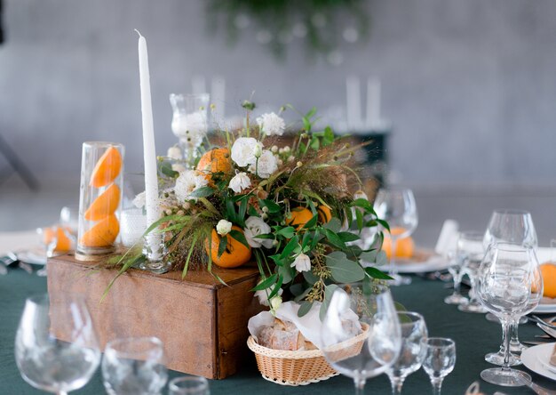 Tabella che serve con composizione floreale con arance sul tavolo verde nel ristorante
