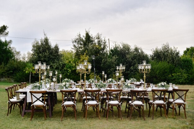 Tabella di celebrazione di cerimonia nuziale decorata con posti a sedere per gli ospiti all'aperto nei giardini
