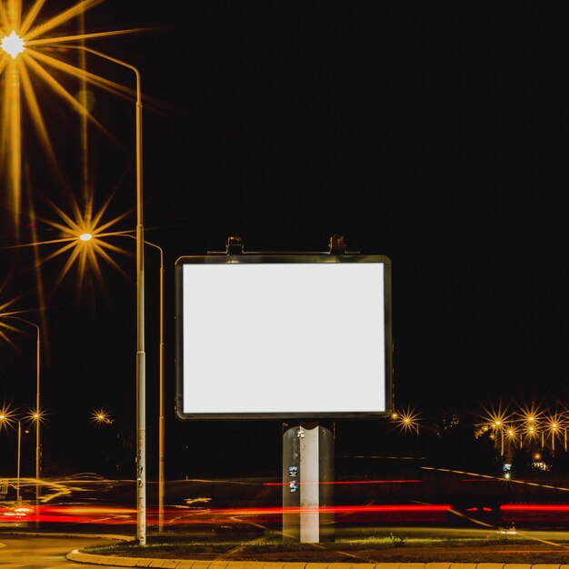 Tabella pubblicitaria bianca con semafori di notte