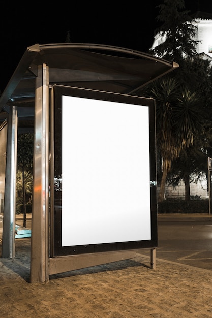 Tabellone per le affissioni di pubblicità in bianco della fermata dell&#39;autobus nella città alla notte