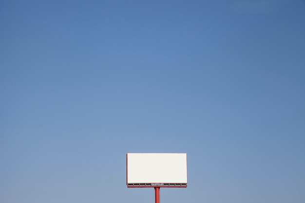 Tabellone per le affissioni tesaurico in bianco contro cielo blu