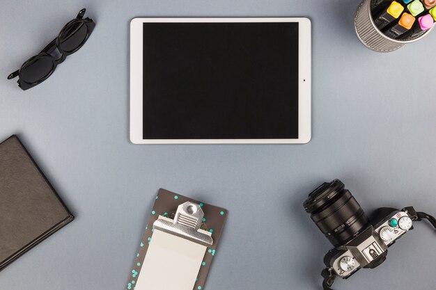 Tablet con notebook e fotocamera sul tavolo