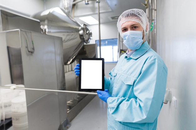 Tablet sul lavoratore medico anteriore in tuta da laboratorio e maschera antigas che mostra tablet vuoto vicino alla macchina steerl