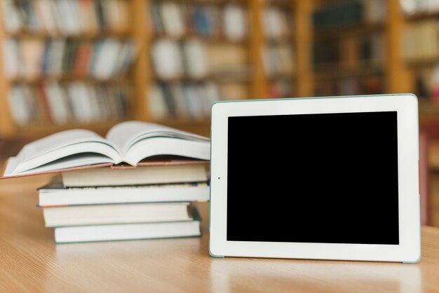 Tablet vicino a pila di libri