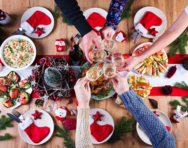 Tacchino al forno. Cena di Natale. La tavola di Natale è servita con un tacchino, decorato con orpelli luminosi e candele. Pollo fritto, tavola. Cena di famiglia. Vista dall'alto, mani nel telaio