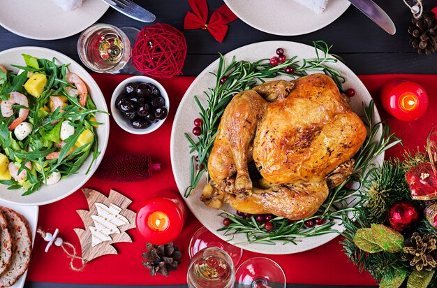 Tacchino Al Forno. Cena di Natale. La tavola di Natale è servita con un tacchino, decorato con orpelli luminosi e candele. Pollo fritto, tavolo. Cena di famiglia. Vista dall'alto