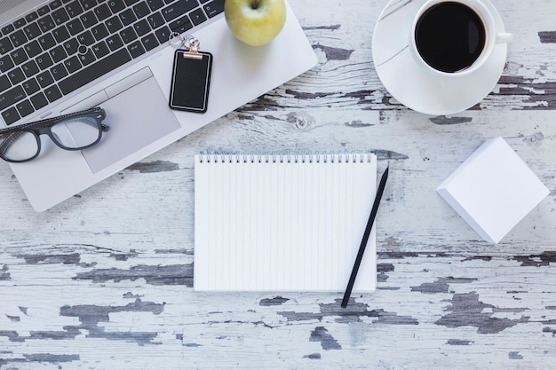 Taccuino con la matita vicino al computer portatile e alla tazza di caffè