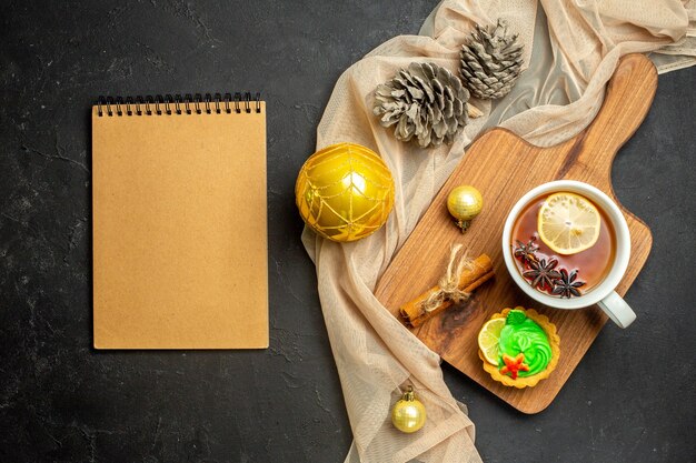Taccuino e una tazza di tè nero con lime e limone e cannella accessori per la decorazione del nuovo anno su tagliere di legno