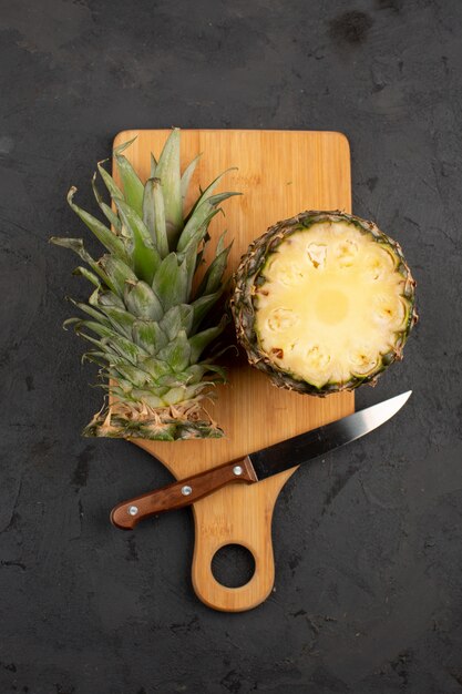 Tagliare l'ananas maturo fresco affettato ananas su uno scrittorio marrone di legno e su un fondo grigio