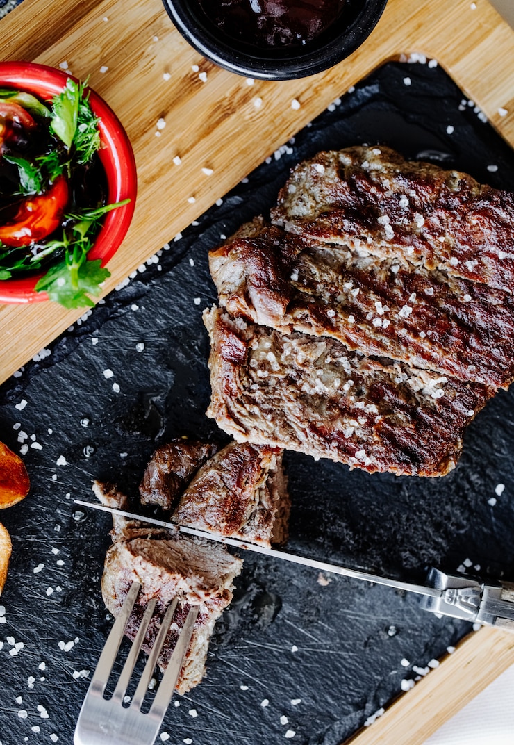 Foto gratuito tagliare la bistecca con coltello e forchetta.