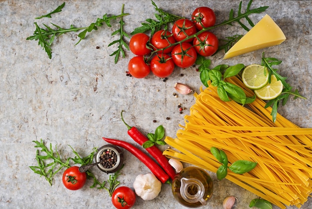 Tagliatelle di pasta e ingredienti per cucinare (pomodori, aglio, basilico, peperoncino). Vista dall'alto