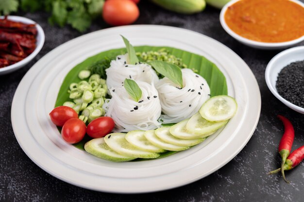 Tagliatelle di riso in una foglia di banana con verdure e contorni splendidamente posati. Cibo thailandese.