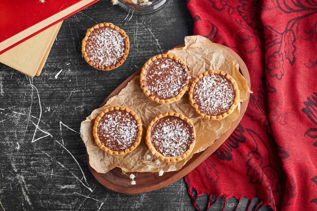 Tartalette al cioccolato con caramello salato su una tavola di legno.