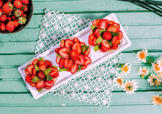 Tartalette rosse della fragola di forma del fiore sulla tavola.