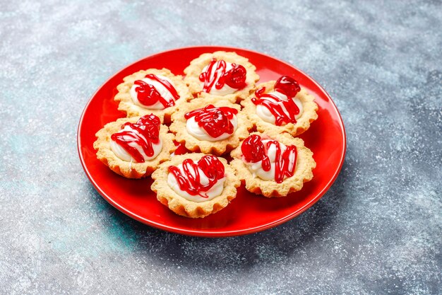 Tartellette con ripieno di cioccolato bianco e confettura di frutti di bosco sopra.