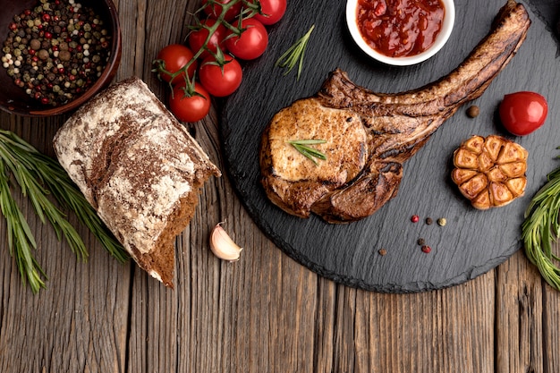 Tavola di legno con carne cotta e pomodori