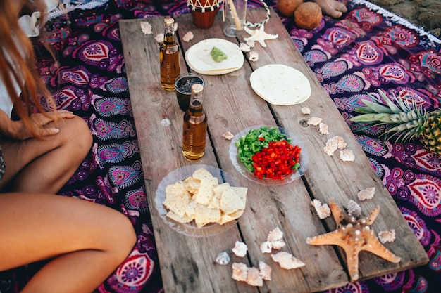 Tavola di legno con cibo e bevande in spiaggia