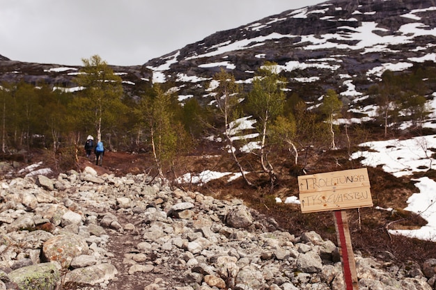 Tavola di legno con scritta 'Trolltunga' si trova sul sentiero per le montagne