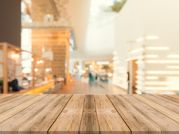 Tavola di legno tabella vuota su sfondo sfocato. Prospettiva tavolo di legno marrone sulla sfocatura nella priorità bassa del caffè - può essere usato mock up per la visualizzazione dei prodotti di montaggio o la disposizione di disegno chiave del disegno.