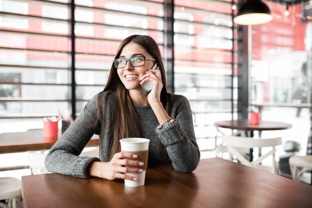 Tavoletta usando il caffè femminile del telefono