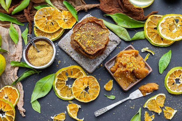 Tavolo con agrumi secchi e frittelle crude vicino a una ciotola piena di marmellata di mandarini