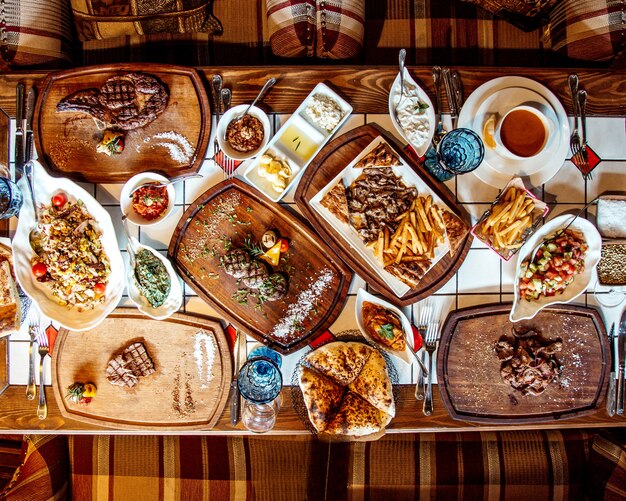 Tavolo da pranzo di insalate, bistecche e patatine fritte