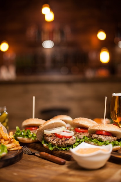 Tavolo da ristorante in legno pieno di deliziosi hamburger e patatine fritte. Hamburger classici. Salsa all'aglio.