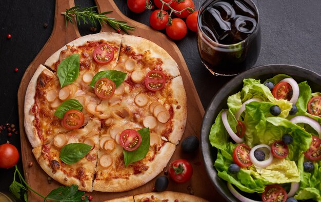Tavolo rustico in pietra scura con vari tipi di pizza italiana, vista dall'alto. Pranzo fast food, celebrazione