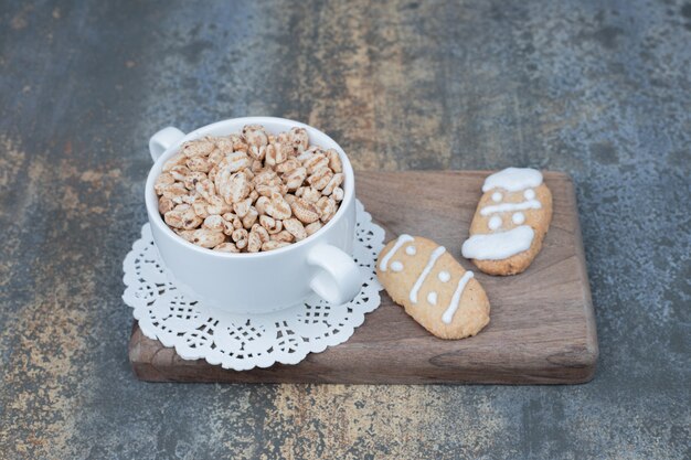 Tazza bianca con due pan di zenzero sulla tavola di legno.