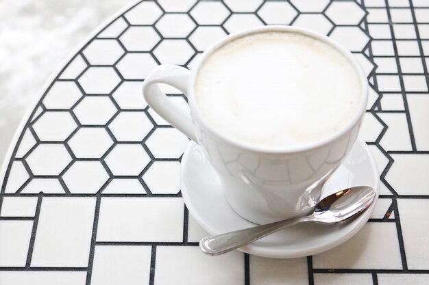 Tazza da tè in ceramica bianca con piattino e cucchiaino in acciaio inossidabile