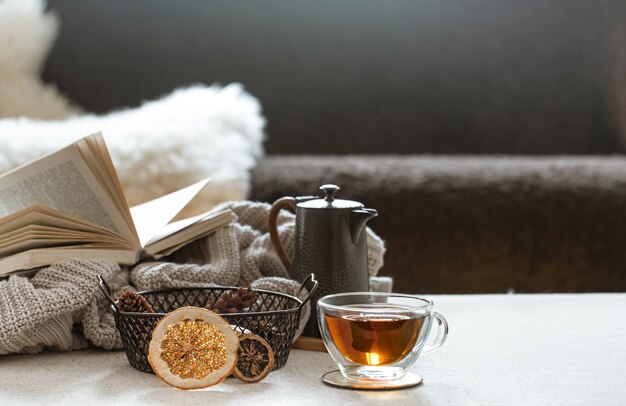 Tazza da tè in vetro, teiera e libro con elemento a maglia sullo spazio sfocato. Il concetto di comfort e calore domestico.