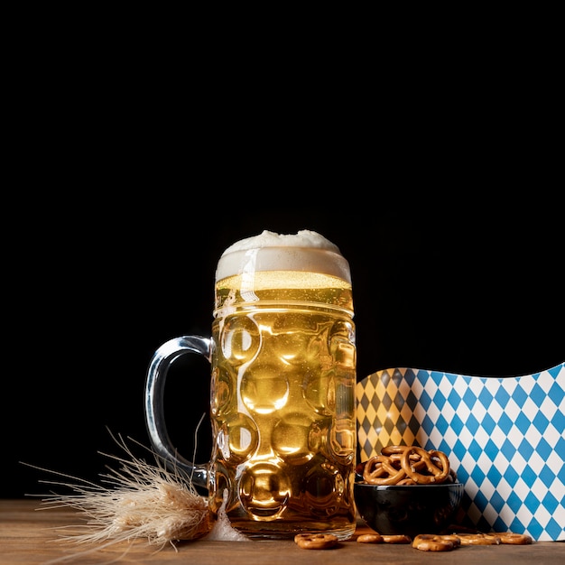 Tazza del primo piano di birra con gli spuntini su una tabella