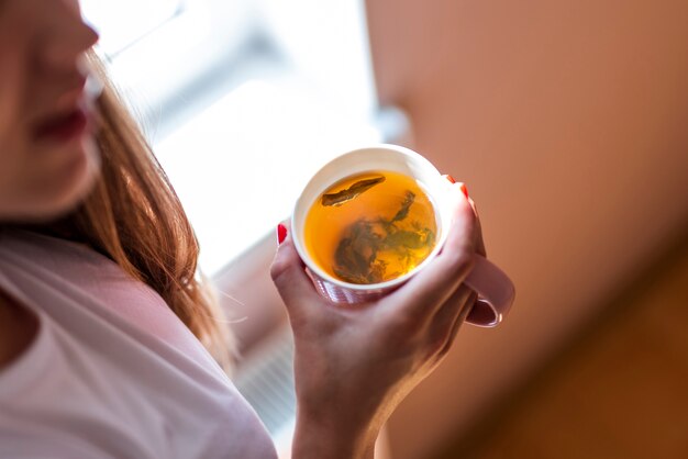 Tazza della holding della donna dell'angolo alto