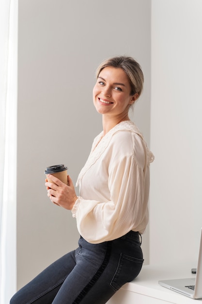 Tazza della holding della donna di smiley del colpo medio