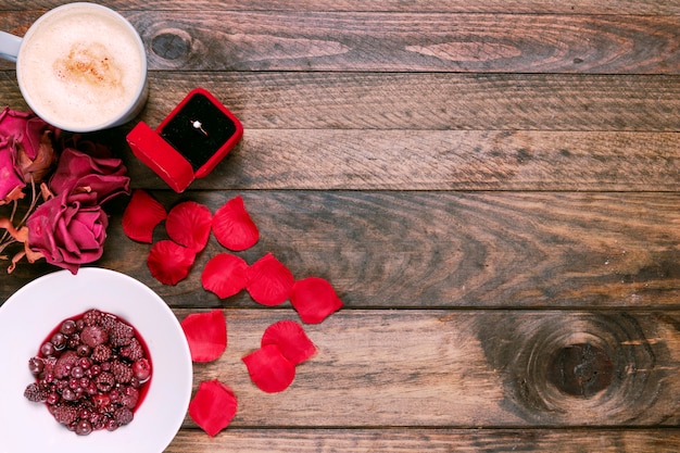 Tazza di bevanda, fiori, marmellata, petali e anello in confezione regalo