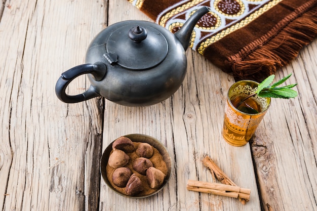 Tazza di bevanda vicino a teiera, stuoia e dolci a bordo