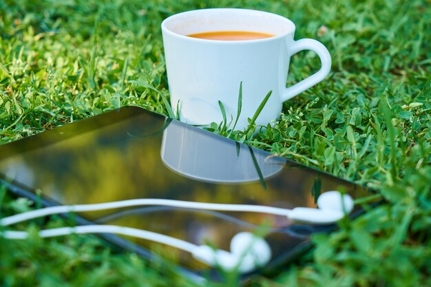 Tazza di caffè accanto a un cellulare con le cuffie