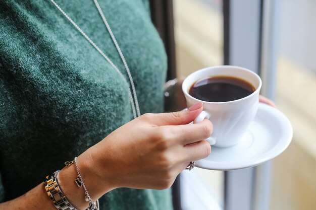 Tazza di caffè bevente della donna di vista laterale