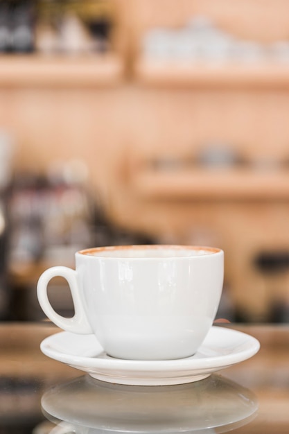 Tazza di caffè bianco sul contatore di vetro riflettente