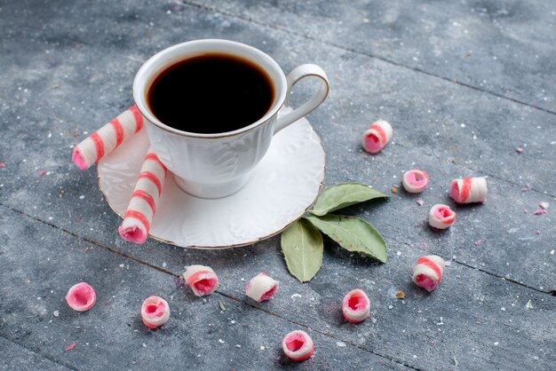 tazza di caffè caldo e forte insieme a caramelle rosa in stick su grigio, bevanda dolce caramelle al caffè