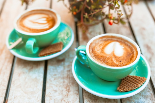 Tazza di caffè con arte del latte di forma del cuore sulla tavola di legno