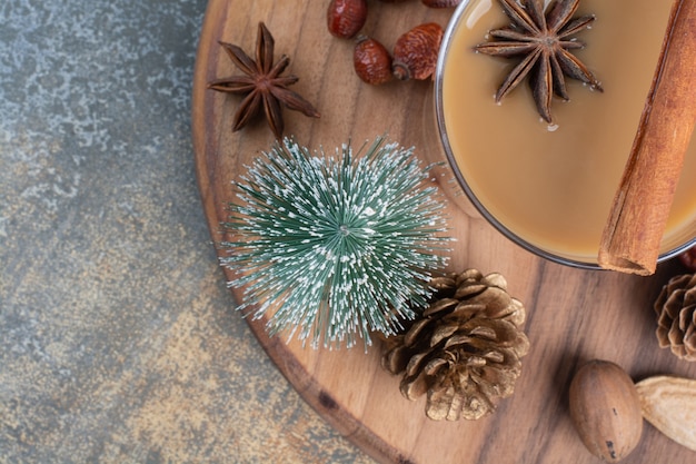 Tazza di caffè con bastoncini di cannella e pigne nelle quali sul piatto di legno. Foto di alta qualità